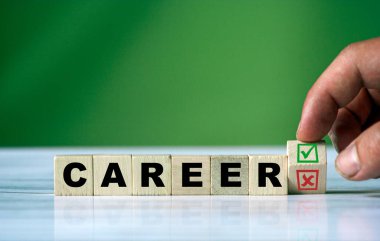 El, tahta küpü döndürür ve yeşil pozitif işaret kutusu ve kırmızı reddetme X işaretli kutusuyla CAREER kelimesini değiştirir..