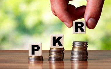 PKR Pakistan para birimi sembolü - iş kavramı. Eller, artan bozuk paraya tahta blok koydu..