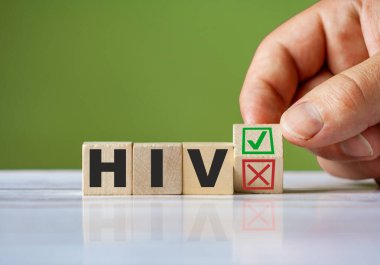 Elin ahşap blokta kırmızı X ve yeşil kene ile dönmesi HIV konseptini değiştirdiğini doğruluyor. HIV kavramsal sembolü kelimesi.