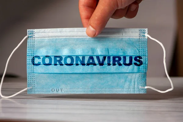 这只手拿着一个带有 Coronavirus 字样的医疗和防护面具 验尸官检疫的概念防止或制止Covid 19在全世界的蔓延 — 图库照片