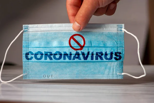 这只手拿着一个带有 Coronavirus 字样的医疗和防护面具 验尸官检疫的概念防止或制止Covid 19在全世界的蔓延 — 图库照片