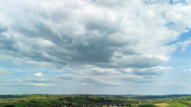 Bulutlarla dolu dramatik bir gökyüzünün altındaki yemyeşil tepelerin manzarası. Bu hareketli manzara, doğa ile olan bağlantıyı ve dinginliği çağrıştırıyor açık hava temaları için ideal..