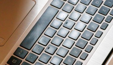 Anahtarları ve dizaynlarını metalik bir yüzeyde gösteren bir dizüstü bilgisayarın yakın çekimi. Teknoloji ve çalışma alanı ile ilgili konular için ideal.