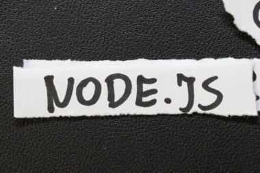 Yırtık bir kağıt şeritte NODE.J.S. gösteren el yazısıyla yazılmış bir metin. Node.js, Chromes V8 motoru üzerine inşa edilmiş bir JavaScript çalışma saatidir..