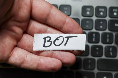 Elinde dizüstü bilgisayarın üzerine yerleştirilmiş siyah mürekkeple yazılmış 