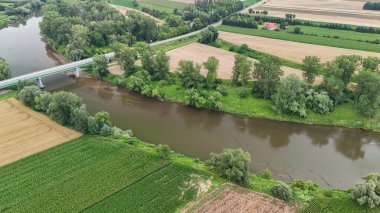 Çayırlarda ve ağaçlarla çevrili yemyeşil manzaralar arasında süzülen sakin bir nehrin havadan görünüşü. Gündüz yakalanan bu sahne doğanın güzelliğini gözler önüne seriyor..