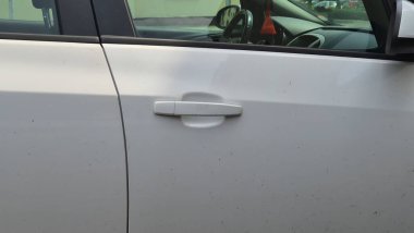 Kirli, beyaz bir araba kapısının yakın plan görüntüsü. Kulplu, kentsel aşınma ve yırtık. Günlük deneyimleri vurgulayan otomotiv ve yaşam tarzı projeleri için ideal.