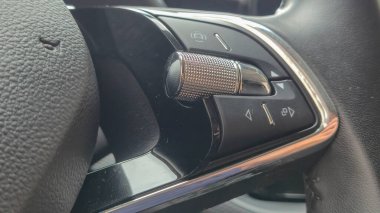 Ses düğmesini ve diğer düğmeleri gösteren modern bir gösterge panelinin yakın çekimi. Pürüzsüz tasarım ve metalik aksanlar teknoloji güdümlü otomotiv deneyimini geliştiriyor.