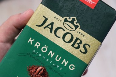 Varşova Polonya - 2 Ağustos 2025: Jacobs Kronung kahve paketini elinde tutan ve özel karışımını ve zengin aromasını sergileyen bir elin yakın çekimi. Kahve severler ve ürün reklamları için ideal..