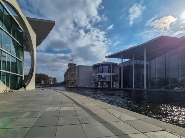 Berlin Almanya - 9 Nisan 2025: Spree Nehri boyunca uzanan modern mimari ikonik binalar, parlak gökyüzü kentsel manzarası. Almanya 'nın çağdaş tasarımını yansıtıyor.