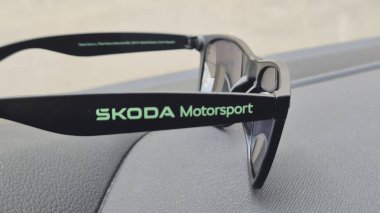 Varşova Polonya - 4 Ağustos 2025: Skoda Motorsport güneş gözlükleri otomotiv kültürü ile yaşam tarzı arasındaki bağlantıyı sembolize eden bir araç panelinde sergilendi.