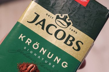 Varşova Polonya - 2 Ağustos 2025: Canlı yeşil tasarımı ve içecek promosyonları için zarif markalaşma ideallerini gözler önüne seren bir Jacobs Kronung kahve paketi.