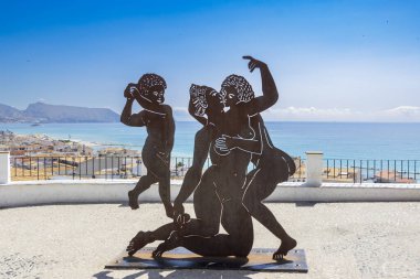 Altea Spain - 17 Temmuz 2025: İnsan figürlerini canlandıran metal heykel deniz sanatının ve kültürünün bir zeminine karşı neşeli bir poz verdi.