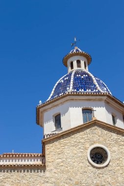 Altea Spain - 17 Temmuz 2025: Akdeniz kültürü ve mirasını temsil eden açık mavi gökyüzüne karşı çarpıcı mavi bir kubbenin yer aldığı tarihi bir kilisenin mimari ayrıntıları.