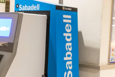 Alicante Spain - 17 Temmuz 2025: Sabadell logosunu gösteren bir ATM makinesi bölgede yerel halk ve turistler için mevcut bankacılık hizmetlerini vurguluyor.