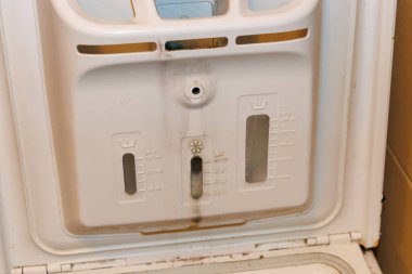 Çamaşır makinesi sabunluğu kompartımanının yakın plan görüntüsü farklı deterjan kapsülleri için ölçüm işaretlerini gösterir ve kolay erişim için tasarlanır..