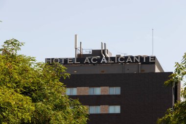 Alicante İspanya - 13 Temmuz 2025: Açık mavi gökyüzüne karşı modern mimari ve yeşil ağaçların yer aldığı Alicante Oteli manzarası.