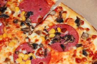 Salam mantarlı ve paket servis edilen mısırlı lezzetli pizzanın yakın çekim görüntüsü. Yemek aşıkları ve mutfak içeriği için mükemmel..