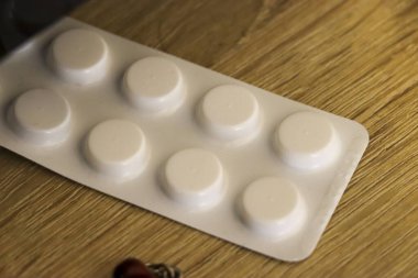 Sağlık ve ilaç kullanımını vurgulayan tahta bir yüzeye yerleştirilmiş su toplayan beyaz hapların yakın plan çekimi. Eczane veya sağlıkla ilgili projeler için ideal.