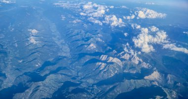 Berrak bir gökyüzü altındaki görkemli dağ sıraları ve vadilerinin havadan görünüşü seyahat temaları için mükemmel dağılmış bulutlarla doğanın güzelliğini gözler önüne seriyor.