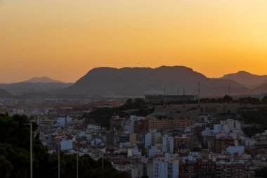 Gün batımında Alicante 'nin panoramik bir görüntüsü dağların arasına yerleşmiş canlı şehir manzarasını gözler önüne seriyor. Gökyüzünün ılık renkleri şehir manzarasını güzelleştirir..