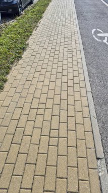 Yeşil çimlerle çevrili ve yola bitişik birbirine kenetlenmiş tuğla desenleri olan geniş kaldırımlar. Kentsel manzara kavramları ve yaya faaliyeti temaları için ideal.