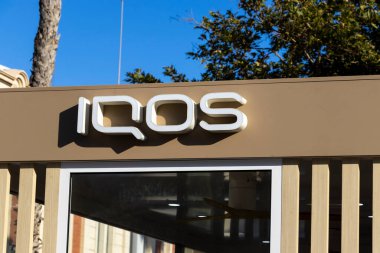 Alicante Spain - July 17 2025: Close-up of an IQOS sign outside a modern establishment showcasing a sleek design and branding. Ideal for advertising and tobacco-related themes.
