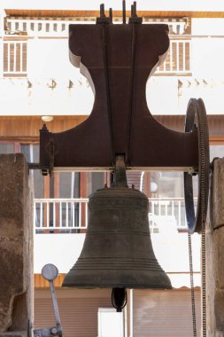 Alicante Spain - July 17 2025: Close-up of an ancient bell showcasing intricate designs framed against local architecture symbolizing history and tradition.
