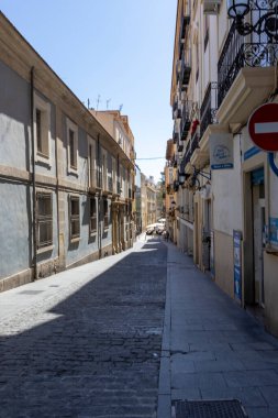 Alicante Spain - July 17 2025: Quiet street in Alicante featuring traditional architecture and cobblestone pavement under clear blue skies perfect for urban exploration.