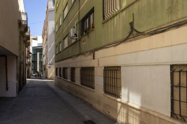 Alicante Spain - July 17 2025: A narrow street scene in Alicante with pastel buildings and cobblestone pavement captured in bright sunlight showcasing local architecture.