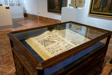 Alicante Spain - July 17 2025: A historic manuscript displayed in a museum showcasing intricate musical notation and colorful illustrations providing cultural insight.