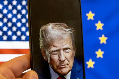 Warsaw Poland - September 17 2025: Image of a smartphone displaying Donald Trump against a backdrop of American and European flags symbolizing political tension and implications of the Ukraine war.