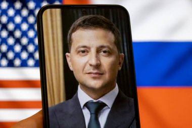 Warsaw Poland - September 17 2025: A smartphone displays a portrait of Volodymyr Zelensky the Ukrainian president. The background features flags of the USA and Russia highlighting the Ukraine war concept.