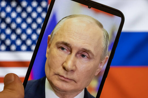 Warsaw Poland - September 17 2025: A close-up of Vladimir Putins face displayed on a smartphone juxtaposed with American and Russian flags symbolizing international tensions.
