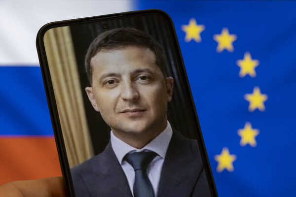 Warsaw Poland - September 17 2025: A close-up of a smartphone displaying Volodymyr Zelensky symbolizing Ukraine war. The Russian and EU flags are in the background.