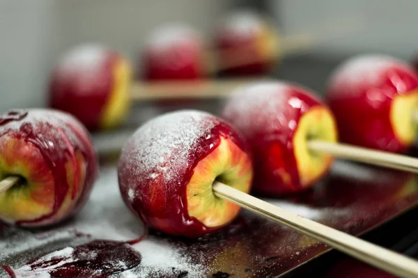 Homemade candy apples with powder sugar on sticks on blur background