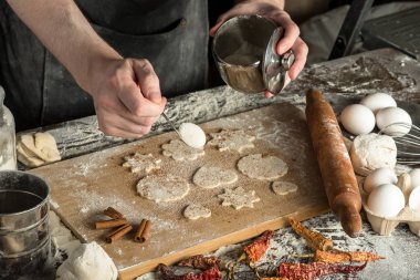 Şefin elleri tahta tahtada çiğ hamura şeker serpiyor. yakın çekim görünümü
