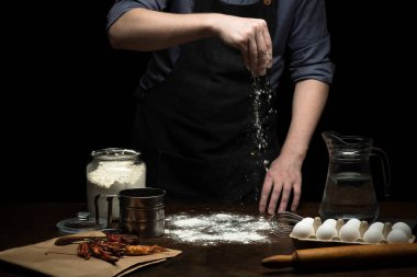 Tahta masada hamur yapmak için un serpiştiriyorum.