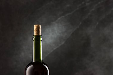 Siyah arka planda mantarlı yeşil şarap şişesi.