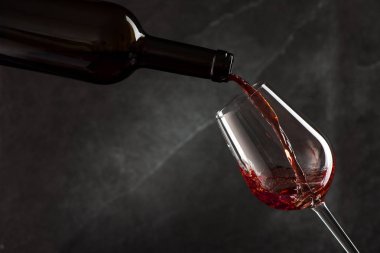 Şarap koyu arkaplandan dökülüyor.
