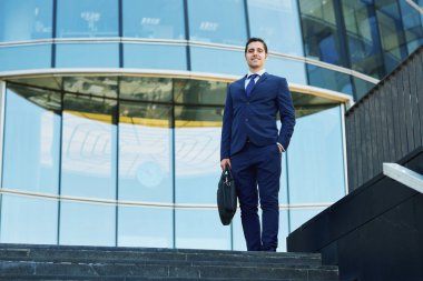 İş merkezinin önünde duran mutlu genç işadamı