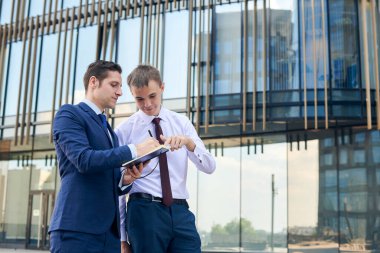 İki iş ortağı dışarıda birlikte çalışıyor. Yönetici projenin yorumlarını yazıyor.