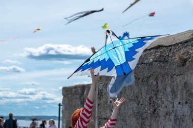 Kız gökyüzündeki uçurtmayı indiriyor.