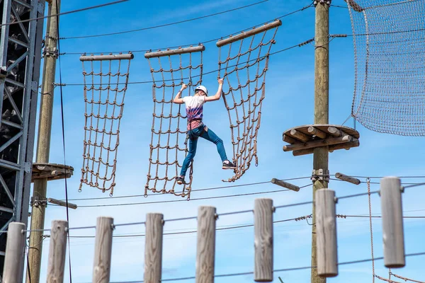 Cesur genç, macera parkında engellerle şebeke yoluna tırmanıyor.