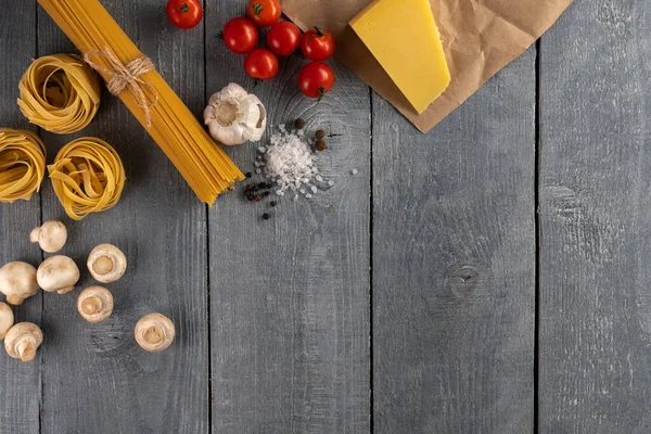 Different ingredients for italian pasta on wooden background with space for text flat lay