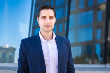 Arkaplanda binaları olan iş elbiseli yakışıklı bir adam.