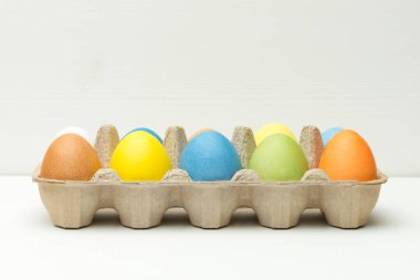 Beyaz ahşap arka plandaki kutuya boyanmış paskalya yumurtaları.