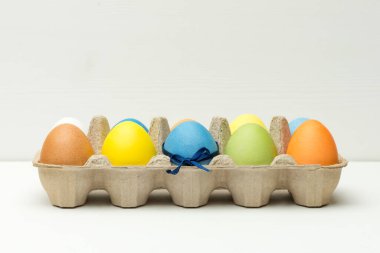 Beyaz ahşap arka plandaki kutuya boyanmış paskalya yumurtaları.