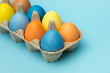 Mavi arka plandaki kutuya boyanmış paskalya yumurtaları.