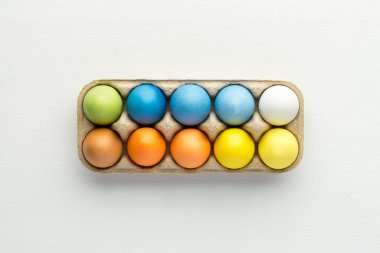 Pastel, beyaz ahşap arka plandaki kutuya paskalya yumurtası boyamış.